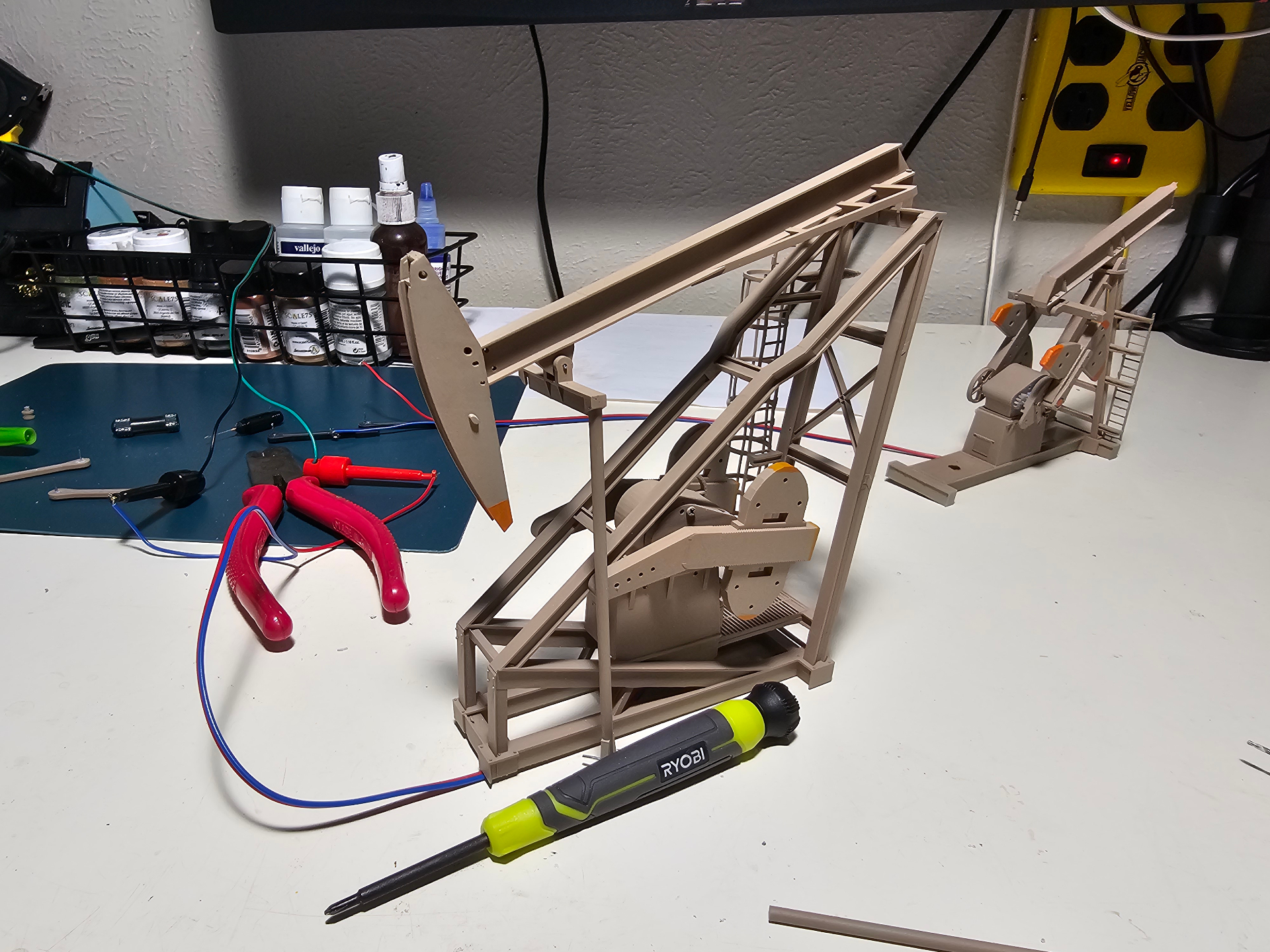 3D-printed resin oil pump jack model with electronic motor kit wired for testing